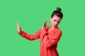 Side view portrait of dissatisfied woman with bun hairstyle in red blouse. indoor studio shot isolated on green background