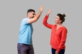 Side view portrait of excited amazed young couple in casual wear giving high five. isolated on gray background