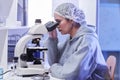 Side view female scientist looking in microscope in laboratory Royalty Free Stock Photo