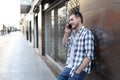 Happy man talks on phone leaning on a wall in the street Royalty Free Stock Photo