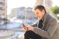 Man using a smart phone in winter in a coast town Royalty Free Stock Photo