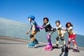 Cute kids rollerblading one after another outdoors