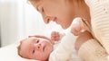 Side view portrait of happy smiling mother stroking and cuddling her newborn baby lying on bed. Concept of family Royalty Free Stock Photo