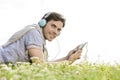 Side view portrait of man listening to music on MP3 player using headphones in park against clear sky Royalty Free Stock Photo