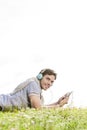 Side view portrait of man listening to music on MP3 player using headphones in park against clear sky Royalty Free Stock Photo