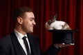 Side view portrait of man magician looking on rabbit appeared in hat Royalty Free Stock Photo