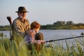 Side view portrait of man and little grandson sitting near river and fishing Royalty Free Stock Photo
