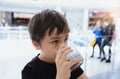 Side view Portrait of mixed race young kid sitting on table drinking cold drink in restaurant, Toodler drinking soda or soft drink Royalty Free Stock Photo