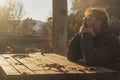 Side view portrait of one man thinking alone worried in outdoor sitting on a table during golden beautiful sunset. People and