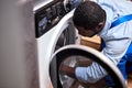 Side view portrait of professional afro technician examining broken washing machine