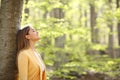 Relaxed woman breathing fresh air in a green forest