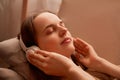 Side view portrait of relaxed young adult woman listening music while resting on couch at home, keeps eyes closed, touching her Royalty Free Stock Photo