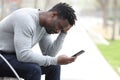 Sad black man complaining checking mobile phone Royalty Free Stock Photo