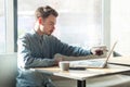 Side view portrait of serious young businessman in blue shirt are sitting and pointing at target on laptop dislpay with attention Royalty Free Stock Photo