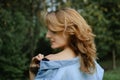 Side view portrait of sexy blonde girl with curly hair wearing blue casual jeans blouse and black lingerie posing in the Royalty Free Stock Photo