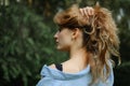 Side view portrait of sexy blonde girl with curly hair wearing blue casual jeans blouse and black lingerie posing in the Royalty Free Stock Photo