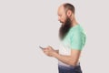 Side view portrait of shocked bald bearded man looking at mobile smart phone display with surprised face. reading good news or Royalty Free Stock Photo