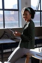 Side view portrait of smiling african american young businesswoman with smart phone in office Royalty Free Stock Photo