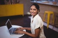 Side view portrait of smiling young woman using laptop at coffee shop Royalty Free Stock Photo