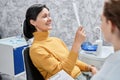 Smilng adult woman looking in mirror in dental