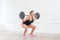 Sporty athletic beautiful woman doing squats and exercising at the gym with the barbell. Royalty Free Stock Photo