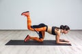 Side view portrait of strong and fit athletic young woman in sportswear with bands training legs and glutes muscular. Fitness