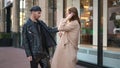 Side view portrait of stylish gay man criticizing young Caucasian woman outfit standing on city street. Confident