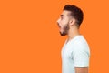 Side view portrait of surprised brunette man looking left with big eyes and open mouth. studio shot  on orange background Royalty Free Stock Photo