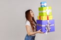 Side view portrait of woman holding stack of presents in hands, having excited facial expression. Royalty Free Stock Photo