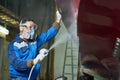 Worker Spray Painting Boats in Workshop