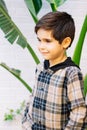 Side view portrait of a 7 years caucasian boy looking aside and smiling in front of a palm plant Royalty Free Stock Photo