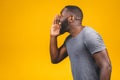 Portrait of a young african american man screaming out loud with hand at his mouth isolated on the yellow background Royalty Free Stock Photo