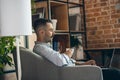 Side view portrait of young businessman working on laptop sitting in comfortable armchair with cup of coffee. Cozy Royalty Free Stock Photo