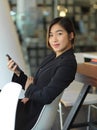 Side view of portrait of young businesswoman in black suit holding smartphone Royalty Free Stock Photo