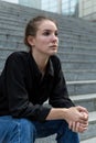 Side View Portrait of Young Caucasian Woman Sitting on Outdoor Steps