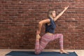 Side view portrait of young fit woman doing sport exercises, variation of One Legged King Pigeon Posture - Eka Pada Rajakapotasana