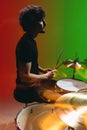 Portrait of young man drummer playing isolated on green-red background in neon Royalty Free Stock Photo