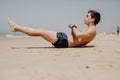 Side view portrait of a young man exercising on the beach doing sit ups Royalty Free Stock Photo