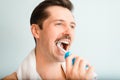 Side view portrait of young man with towel on shoulders brushing white teeth with modern electric toothbrush, close-up. Royalty Free Stock Photo