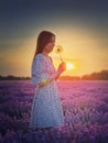 Side view portrait of a young woman in lavender field holding a blowball dandelion against the sunset background. Natural summer Royalty Free Stock Photo