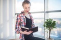 Side view portrait of young woman sitting, looking down, reading the book, learning at light room in morning with her Royalty Free Stock Photo