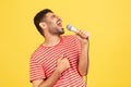 Side view positive bearded man in striped t-shirt loudly singing song holding microphone in hand, having fun resting in karaoke,