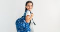 Side view of positive schoolgirl with blue backpack smiling and looking at camera. Pretty schoolkid with backpack has joyful Royalty Free Stock Photo