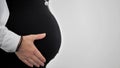 Side view of a pregnant woman holding her hand on her tummy. Isolated on white background. Royalty Free Stock Photo