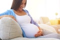 Pregnant woman on sofa caressing her belly Royalty Free Stock Photo