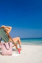 Side view of pretty brunette relaxing on deck chair at the beach Royalty Free Stock Photo