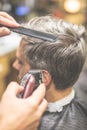 Side view of professional barber styling hair of his client by using comb and clipper Royalty Free Stock Photo
