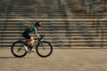 Side view of professional female cyclist in cycling garment and protective gear riding bicycle in city, rushing and