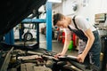 Side view of professional handsome professional male car mechanic in blue uniform standing in front of open hood. Royalty Free Stock Photo