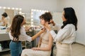 Side view of professional makeup artist applying foundation brush on neck body of young woman model. Hairdresser doing Royalty Free Stock Photo